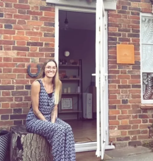 Leanne sitting outside her reflexology business, inviting clients to experience holistic healing.